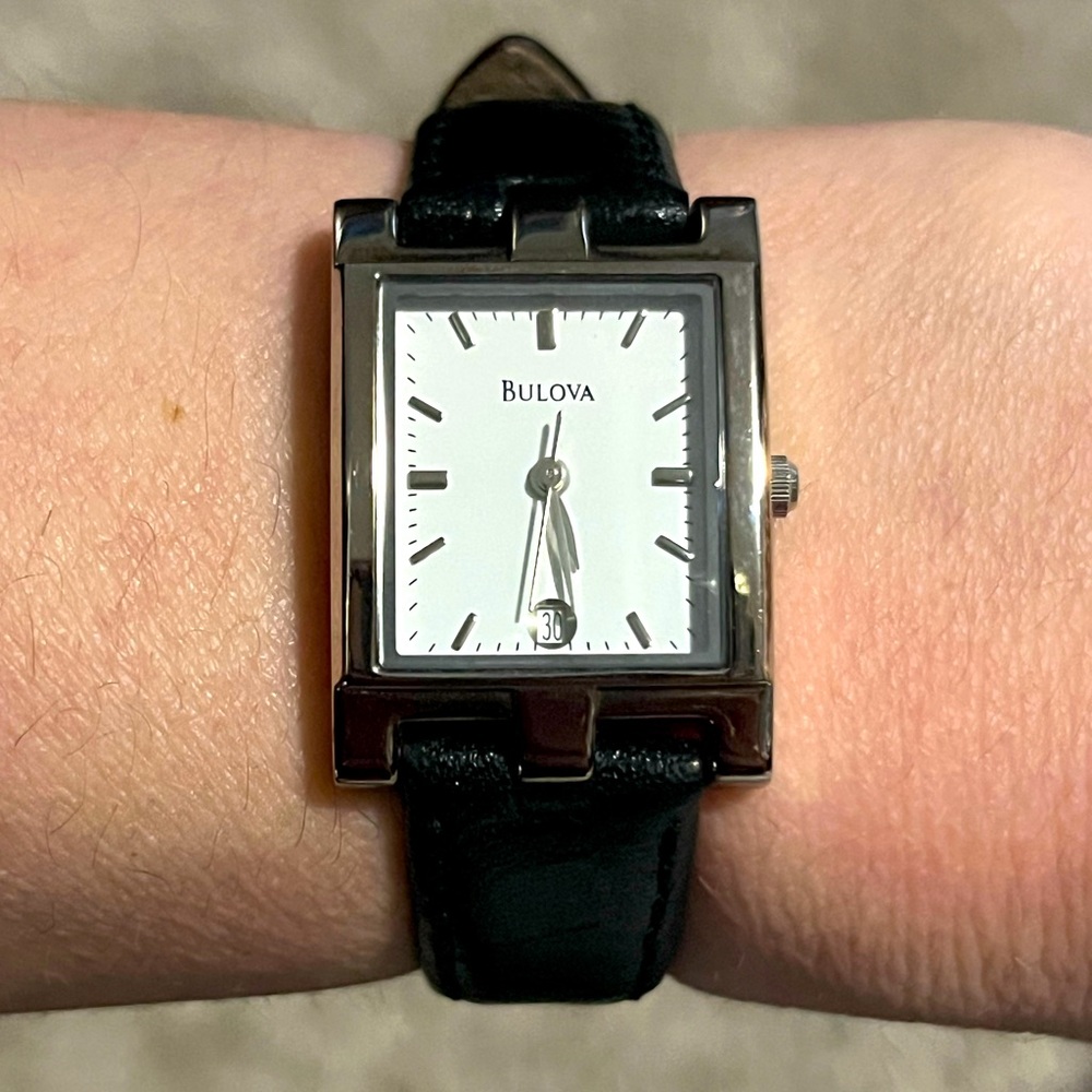 Bulova stainless steel tank watch with a black leather strap.